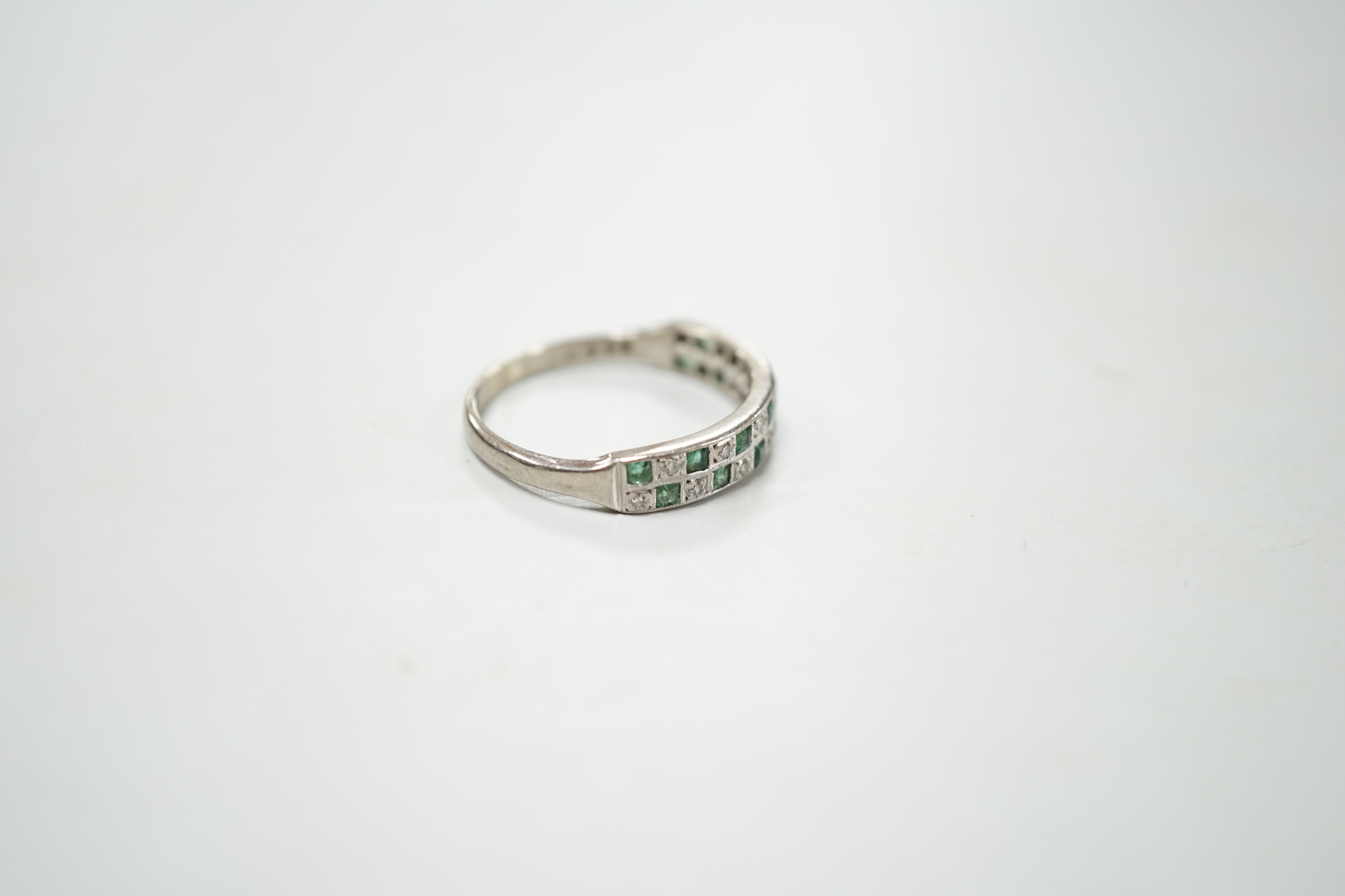 A modern 18ct white gold and two row emerald and diamond cluster set half hoop ring, size S, gross weight 4.5 grams.